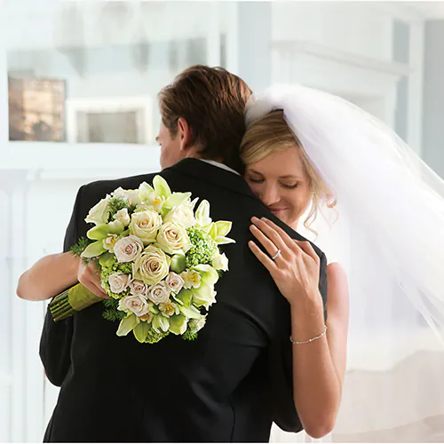 Bride hugging groom while holding a bouquet